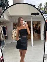 Pollera corta negra de ecocuero, con cortes y detalles de bolsillos grandes.