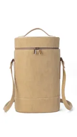 Matera cilíndrica color beige, con tapa superior con cierre, asa de mano y correa larga regulable para llevar al hombro.