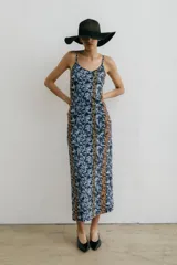 Vestido midi de tirantes finos con estampado floral en tonos azul, negro y naranja. Tiene escote redondo y tajo lateral.