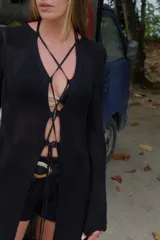 Saco largo de tejido de punto negro con diseño calado y acordonado en el frente, de manga larga.