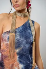 Conjunto de falda larga y top asimétrico con estampado tie-dye en tonos azul, naranja y marrón. El top es de un solo hombro y tiene un collarín con flecos dorados.