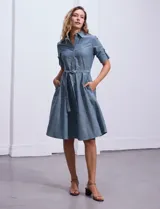 Vestido camisero blanco de algodón con cuello con solapa, delantera abotonada, mangas 3/4 regulables con presilla y botón, y cintura con lazo de ajuste.