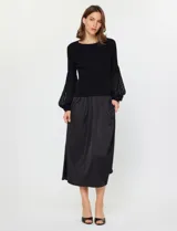 Conjunto de dos piezas compuesto por un sweater negro de punto acanalado con mangas globo de organza transparente y una falda midi negra de satén con caída suelta y cintura elastizada.