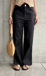 Pantalón negro de lino, de corte recto, con pinzas en la cintura y aberturas laterales en el ruedo.