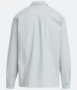 Camisa celeste de algodón, corte oversized, manga larga, cuello camisero, dos bolsillos frontales con solapa y cierre con botones.