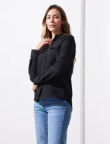Camisa negra de manga larga con cuello con solapa y abertura central con botones. Delantera con bolsillos aplicados.