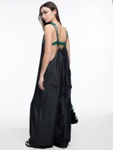 Mono largo de denim azul oscuro, con breteles finos regulables, escote recto, bolsillos traseros y corte amplio de pierna recta.