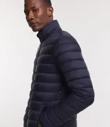 Campera puffer ultraligera color beige, con cuello alto, cierre por cremallera y bolsillos con cremallera. Incluye bolso de almacenamiento.