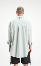 Camisa celeste de manga larga con bolsillo ojal en delantero, cartera escondida y calce oversize.