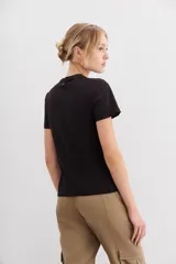 Remera negra de algodón con calce al cuerpo, mangas cortas y cuello redondo. Presenta un bordado frontal de abeja con canutillos dorados y plateados.