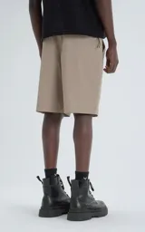 Bermuda estilo técnico color beige, confeccionada en microfibra liviana. Presenta cintura elástica con cinturón integrado de cinta negra con hebilla de plástico. Cuenta con múltiples bolsillos cargo, incluyendo uno lateral con panel de malla.