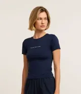 Remera deportiva azul marino de microfibra con cuello redondo, mangas cortas y estampa frontal con la frase "be your own muse".
