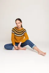 Sweater tejido a mano color mostaza con diseño geométrico en el canesú en tonos azul marino, blanco y verde.