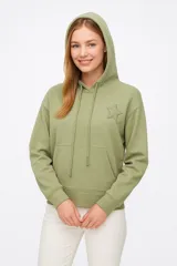 Buzo verde con capucha, cordones ajustables y bolsillo tipo canguro. Presenta un logo bordado con forma de estrella en el pecho.