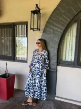 Vestido largo con estampado abstracto en blanco y azul, cuello en V y mangas largas abullonadas.