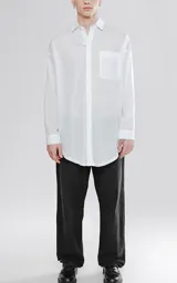 Camisa manga larga blanca de calce oversize confeccionada en textil fresco y liviano, con bolsillo ojal en delantero y cartera escondida.