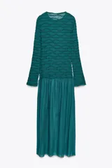Vestido midi color verde esmeralda con textura plisada en la parte superior y falda lisa. Tiene cuello redondo y mangas largas.