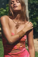 Collar rígido metálico tipo choker color dorado, con colgante en forma de coral en relieve.