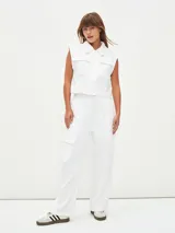 Pantalón de vestir blanco, de tiro alto y corte palazzo, con bolsillos laterales y bolsillos cargo con solapa en los muslos.