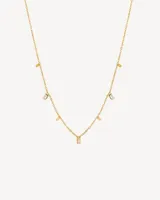 Set de tres gargantillas doradas de diferentes largos. La primera es una cadena de eslabones rectangulares, la segunda es una cadena fina con dijes rectangulares colgantes y la tercera es una cadena gruesa de eslabones apretados.