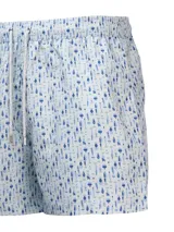 Short de baño celeste con estampado de ballenas en azul y gris. Tiene cintura elástica con cordón ajustable y bolsillos laterales.
