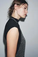 Top plateado de anillas metálicas con cuello halter y hombros descubiertos. Se cierra con mosquetón en cuello y espalda.