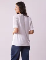 Blusa blanca de algodón con escote en V, abertura con botones y mangas cortas con detalle de broderie.