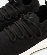 Championes de poliéster negro con suela blanca, cierre con cordones y tirador en el talón.