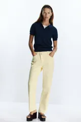 Jeans tobilleros de tiro alto color blanco, corte recto y cinco bolsillos. Cierre frontal cruzado con cremallera y botones.
