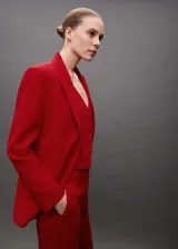 Traje sastrero rojo compuesto por blazer de corte recto con solapas de muesca y cierre de doble botón, chaleco con escote en V y pantalón de vestir de corte recto.