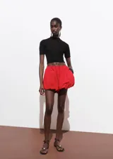 Jersey de punto fino color negro, manga corta, cuello perkins y diseño crop ajustado.