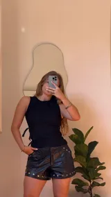 Top negro de gabardina elastizada, sin mangas, con tiras ajustables en la parte delantera y cierre en la espalda.