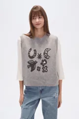 Chaleco de punto sin mangas confeccionado en rayón con efecto confetti en color gris melange. Presenta un diseño frontal en jacquard con diversos motivos como una herradura, una luna, un pájaro y estrellas, con cuello redondo y terminaciones acanaladas.