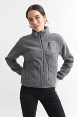 Campera negra de corderito con cierre frontal y cuello alto. Tiene un bolsillo con cierre en el pecho y bolsillos laterales.