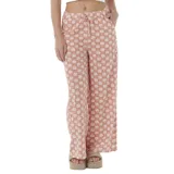 Pantalón Rip Curl de corte amplio, color salmón con estampado de flores blancas, cintura alta con cordón ajustable y bolsillos laterales.