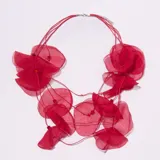 Collar de tela roja con múltiples pétalos de organza superpuestos y cuentas pequeñas de color naranja. El cierre es de mosquetón metálico con cadena de alargue.