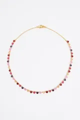 Collar dorado con cadena fina y dijes de corazones de cristal en tonos rosa, rojo y violeta.