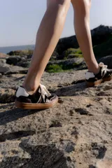 Zapatillas bajas de cuero color marrón oscuro con detalles en blanco y suela de goma color caramelo.