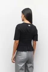 Remera de algodón negra con fruncidos en la cintura y mangas cortas, diseñada con un corte ajustado.