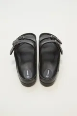 Sandalias planas color beige con doble tira y hebillas ajustables.