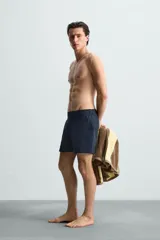 Short de baño celeste de tejido técnico con cintura elástica ajustable con cordón interior y trabillas laterales. Tiene bolsillos frontales y bolsillo trasero con cierre de cremallera. Cuenta con forro interior y cierre frontal con cremallera y botón a presión oculto.