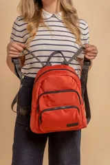 Mochila funcional color beige con detalles en negro, que incluye dos compartimentos con cierre y un bolsillo frontal para fácil acceso.