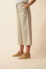 Pantalón palazzo color beige, de tiro alto, con bolsillos laterales y largo a la pantorrilla.