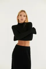 Polera negra de punto calado con cuello alto y mangas largas con ojal para el pulgar.