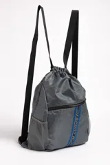 Mochila gris oscuro con cierre de cordón ajustable y tiras negras. Tiene un bolsillo frontal con cierre y dos bolsillos laterales de red.