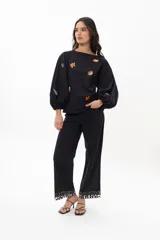 Blusa color arena de algodón con escote a la base y mangas abullonadas. Presenta bordados artesanales de motivos marinos en tonos naranja y azul.