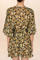 Cover up corto de estilo bohemio con estampado en tonos amarillos, naranjas y negros. Presenta un diseño de tela ligera y traslúcida con escote en V, botones frontales y mangas largas con puños elásticos. Incluye un cinturón de lazo ajustable en la cintura y un ruedo con terminación en volados.