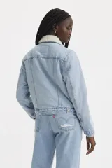 Campera de jean celeste claro con cuello de piel sintética blanca, bolsillos frontales con solapa y cierre con botones metálicos.