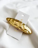Broche de pelo dorado con acabado martillado, diseño elegante y minimalista.
