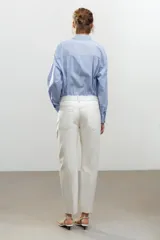 Pantalón de jean color crudo, de tiro medio, corte tapered, con cinco bolsillos y raya planchada en el frente.